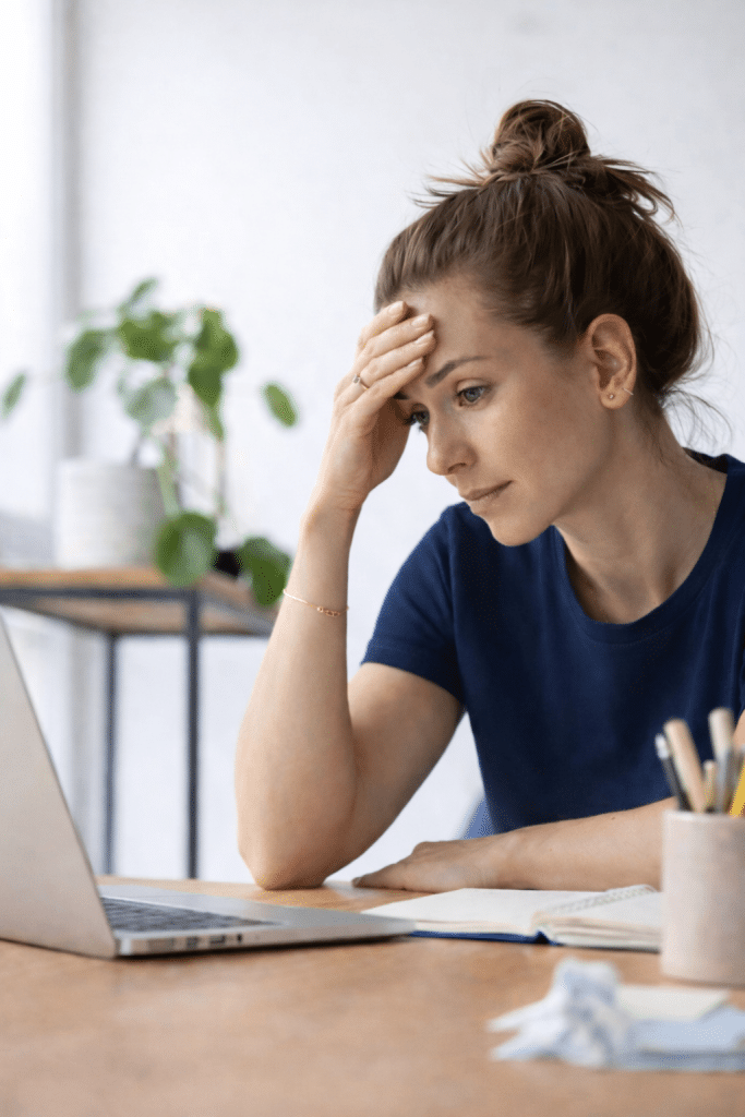 Overwhelmed female business owner looking at laptop on desk